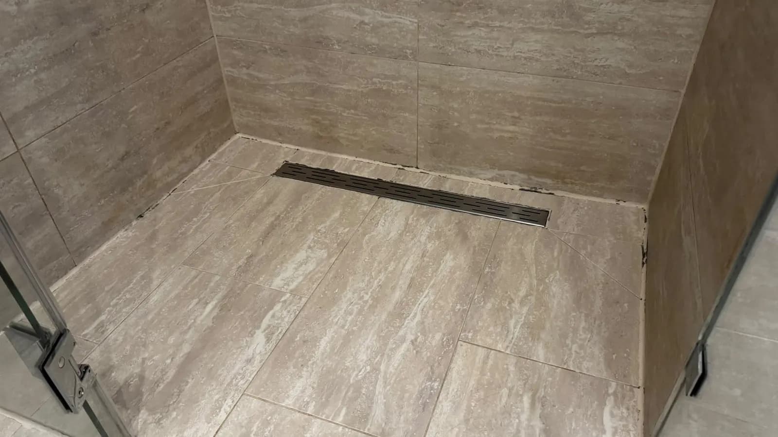 Alte, verschmutzte Silikonfugen in einer Walk-in-Dusche mit Duschrinne, Vorher